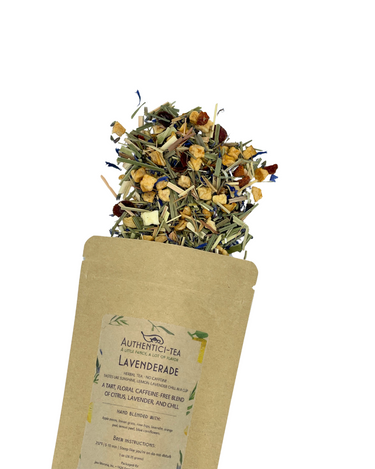 A brown pouch labeled 💜🍋 Lavenderade – Tart, Chill, and Drama-Free is open, showing a caffeine-free blend of vibrant dried lavender, citrus pieces, and lemongrass spilling out against a white background.
